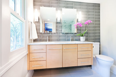 Large transitional master gray tile white floor corner shower photo in Minneapolis with flat-panel cabinets, medium tone wood cabinets, white walls, an undermount sink and a hinged shower door