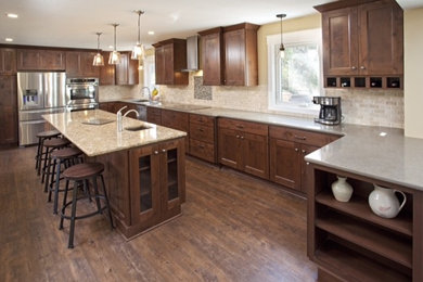 Huge mountain style u-shaped medium tone wood floor eat-in kitchen photo in Minneapolis with a double-bowl sink, recessed-panel cabinets, dark wood cabinets, quartz countertops, beige backsplash, stone tile backsplash, stainless steel appliances and an island