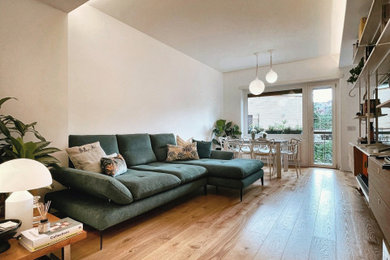 Foto di un soggiorno scandinavo di medie dimensioni e aperto con libreria, pareti bianche, parquet chiaro e TV a parete