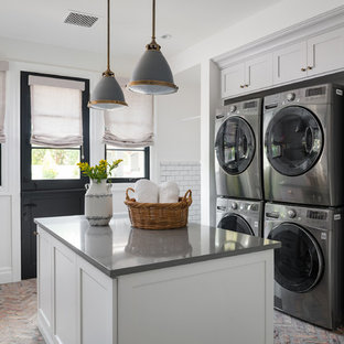 フェニックスのトランジショナルスタイルのおしゃれなランドリールーム (シェーカースタイル扉のキャビネット、グレーのキャビネット、白い壁、レンガの床、上下配置の洗濯機・乾燥機、赤い床、グレーのキッチンカウンター) の写真