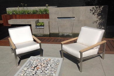 Mid-sized contemporary backyard patio in Edmonton with a water feature, concrete slab and no cover.