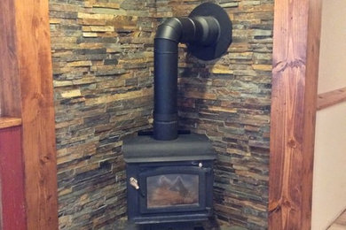 Inspiration for a mid-sized rustic open concept medium tone wood floor and beige floor family room remodel in Wichita with white walls, a wood stove, a stone fireplace and no tv