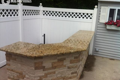 Example of a large classic backyard stone patio kitchen design in New York