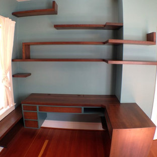This is an example of a modern home office and library in Portland with blue walls, medium hardwood flooring and a built-in desk.