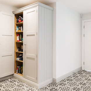 ケントの巨大なコンテンポラリースタイルのおしゃれな家事室 (シェーカースタイル扉のキャビネット、グレーのキャビネット、セラミックタイルの床、左右配置の洗濯機・乾燥機、シングルシンク、ラミネートカウンター、グレーの壁、黄色い床、グレーのキッチンカウンター) の写真