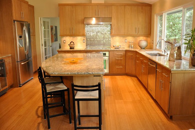 Light wood floor kitchen photo in Portland with light wood cabinets, granite countertops, metallic backsplash, stainless steel appliances and an island