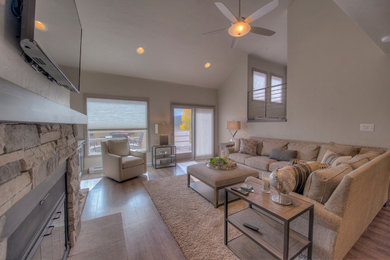Example of a mid-sized transitional formal and open concept vinyl floor and gray floor living room design with a hanging fireplace, a stone fireplace and a wall-mounted tv