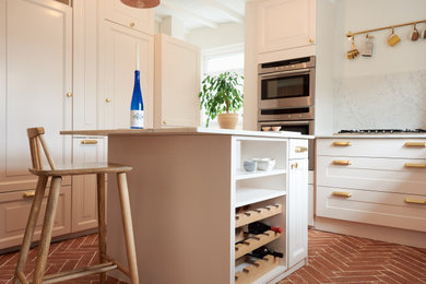 This is an example of a kitchen in Other with shaker cabinets, pink cabinets, terracotta flooring, an island, red floors and white worktops.