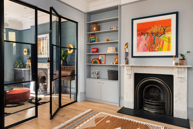 Design ideas for a medium sized victorian living room in London with blue walls, laminate floors, a standard fireplace, a stone fireplace surround, brown floors, wallpapered walls and feature lighting.