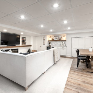 Medium sized classic fully buried basement in Milwaukee with white walls, laminate floors, a standard fireplace, a wooden fireplace surround and brown floors.