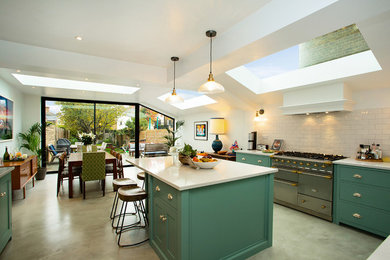 Transitional l-shaped eat-in kitchen in London with shaker cabinets, green cabinets, with island and white benchtop.
