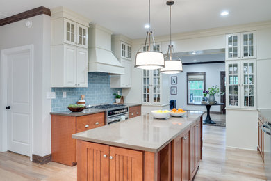 Inspiration for a mid-sized transitional u-shaped light wood floor enclosed kitchen remodel in Orange County with flat-panel cabinets, medium tone wood cabinets, solid surface countertops, blue backsplash, subway tile backsplash, stainless steel appliances and an island