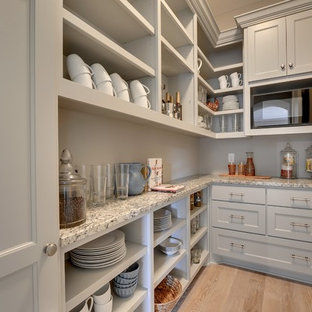 Inspiration pour une grande arrière-cuisine traditionnelle en L avec un évier de ferme, un placard avec porte à panneau encastré, des portes de placard blanches, une crédence grise, une crédence en carrelage métro, un électroménager en acier inoxydable, un sol en bois clair et un îlot central.