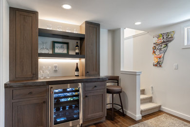 Inspiration for a transitional brown floor home bar remodel in Burlington with shaker cabinets, dark wood cabinets and black countertops