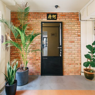 Bild på en eklektisk entré, med vita väggar, betonggolv, en enkeldörr, en svart dörr och grått golv