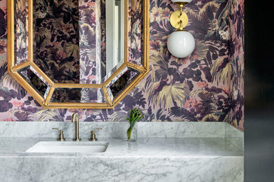 Trendy medium tone wood floor and brown floor powder room photo in Houston with multicolored walls, an undermount sink and white countertops