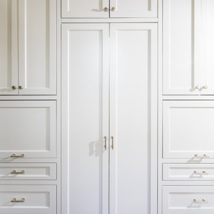 Inredning av ett klassiskt mellanstort vit vitt skafferi, med en rustik diskho, luckor med profilerade fronter, vita skåp, bänkskiva i kvarts, vitt stänkskydd, stänkskydd i porslinskakel, integrerade vitvaror, ljust trägolv, en köksö och brunt golv