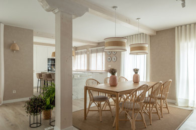 Пример оригинального дизайна: большая гостиная-столовая в стиле неоклассика (современная классика) с бежевыми стенами, полом из ламината, стандартным камином, фасадом камина из каменной кладки, балками на потолке и обоями на стенах