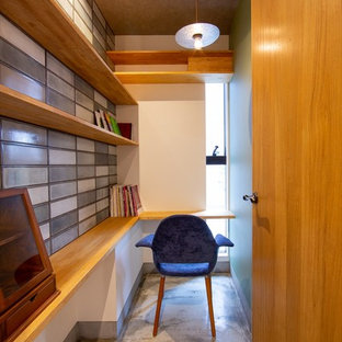 Photo of a small modern home office and library with multi-coloured walls, a built-in desk and grey floors.