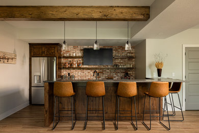 Large transitional walk-out vinyl floor, brown floor, exposed beam and brick wall basement photo in Kansas City with a bar and gray walls