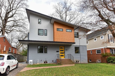 Mid-sized modern three-storey multi-coloured house exterior with mixed siding.