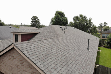 Ejemplo de fachada de casa gris de una planta con tejado de teja de madera