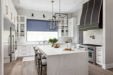 Example of a trendy kitchen design in Houston with shaker cabinets, white cabinets, quartzite countertops, stone slab backsplash, stainless steel appliances, an island and white countertops