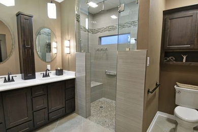 Large transitional master multicolored tile and stone tile ceramic tile and beige floor walk-in shower photo in Miami with shaker cabinets, dark wood cabinets, a one-piece toilet, beige walls, an undermount sink, solid surface countertops and a hinged shower door