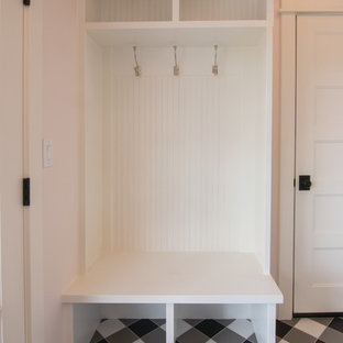 Photo of a small farmhouse u-shaped utility room in Other with a belfast sink, pink walls, ceramic flooring, a side by side washer and dryer and black floors.