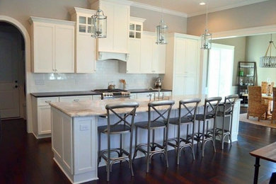 Inspiration for a mid-sized transitional galley dark wood floor eat-in kitchen remodel in Columbus with a farmhouse sink, shaker cabinets, white cabinets, marble countertops, white backsplash, subway tile backsplash, paneled appliances and an island