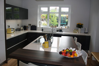 Inspiration for a medium sized modern u-shaped open plan kitchen in Other with a built-in sink, flat-panel cabinets, black cabinets, granite worktops, integrated appliances, medium hardwood flooring and an island.