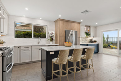 Example of a large trendy l-shaped porcelain tile and gray floor eat-in kitchen design in San Diego with an undermount sink, shaker cabinets, gray cabinets, quartz countertops, white backsplash, glass tile backsplash, stainless steel appliances, an island and gray countertops