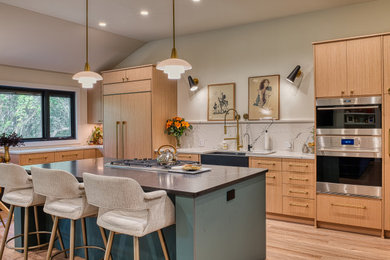 Mid-sized 1960s l-shaped vinyl floor, brown floor and vaulted ceiling open concept kitchen photo in Other with a farmhouse sink, flat-panel cabinets, light wood cabinets, quartz countertops, white backsplash, quartz backsplash, stainless steel appliances, an island and white countertops