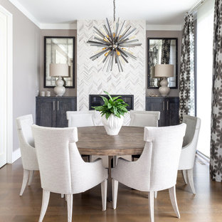 Exemple d'une salle à manger chic avec un mur gris, un sol en bois brun, une cheminée standard, un manteau de cheminée en carrelage et un sol marron.