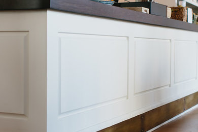 Open concept kitchen - mid-sized modern galley concrete floor open concept kitchen idea in Atlanta with raised-panel cabinets, white cabinets, wood countertops, white backsplash and an island