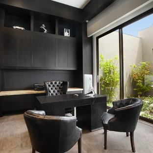 Foto på ett funkis arbetsrum, med svarta väggar, heltäckningsmatta och ett fristående skrivbord