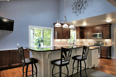 Eat-in kitchen - large transitional l-shaped medium tone wood floor eat-in kitchen idea in Other with shaker cabinets, granite countertops, stone tile backsplash, stainless steel appliances, an island, a single-bowl sink, dark wood cabinets and white backsplash