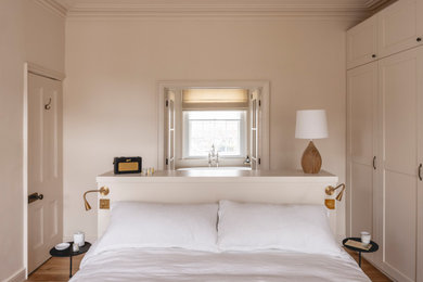 Inspiration for a classic master bedroom in Hampshire with beige walls and light hardwood flooring.