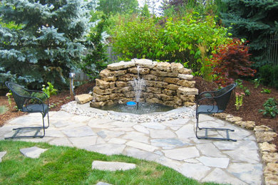 Inspiration for a transitional backyard stone patio fountain remodel in Toronto with no cover