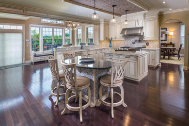 Inspiration for a large timeless l-shaped dark wood floor, brown floor and wood ceiling eat-in kitchen remodel in Philadelphia with an undermount sink, raised-panel cabinets, white cabinets, granite countertops, white backsplash, stone tile backsplash, stainless steel appliances, two islands and white countertops