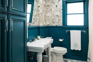 Inspiration for a mid-sized craftsman ceramic tile, multicolored floor and wallpaper powder room remodel in Dallas with a two-piece toilet, blue walls, a pedestal sink and a freestanding vanity