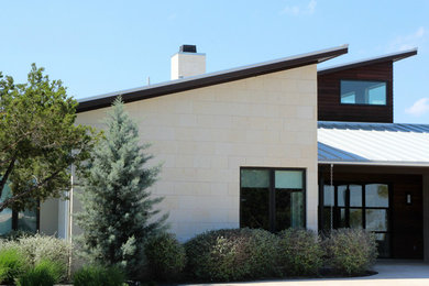 Large trendy white one-story stone exterior home photo in Austin with a shed roof