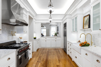 フィラデルフィアにあるトランジショナルスタイルのおしゃれなキッチン (エプロンフロントシンク、白いキャビネット、大理石カウンター、石タイルのキッチンパネル、シルバーの調理設備、白いキッチンカウンター) の写真