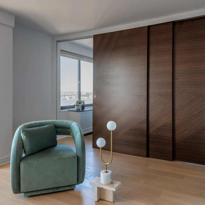 This space exudes modern elegance with a focus on clean lines and luxurious materials. The room features a stunning Italian made sliding door made of rich wood with a geometric pattern, creating a bol