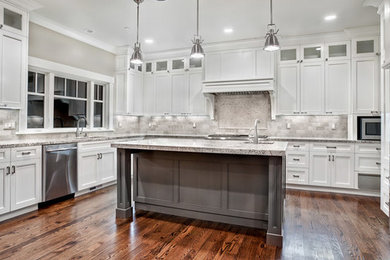 Photo of a large contemporary u-shaped open plan kitchen in Detroit with a drop-in sink, white cabinets, granite benchtops, white splashback, stainless steel appliances, dark hardwood floors, with island and brown floor.