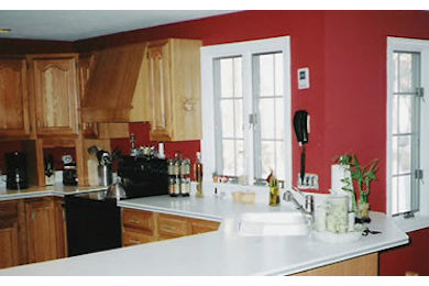 Exempel på ett kök, med skåp i mellenmörkt trä, rött stänkskydd och svarta vitvaror