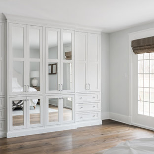 Foto de armario y vestidor unisex, de estilo de casa de campo, de tamaño medio, con armarios con paneles lisos, puertas de armario blancas, suelo de madera en tonos medios y suelo marrón