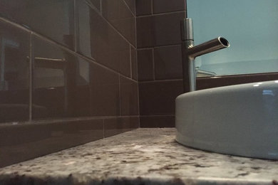 Inspiration for a coastal 3/4 brown tile and subway tile double shower remodel in Orlando with flat-panel cabinets, gray cabinets, a one-piece toilet, brown walls, a vessel sink and granite countertops