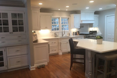 Eat-in kitchen - mid-sized transitional u-shaped medium tone wood floor and brown floor eat-in kitchen idea in New York with an undermount sink, shaker cabinets, white cabinets, quartzite countertops, white backsplash, subway tile backsplash, stainless steel appliances and an island