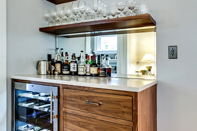 Example of a small urban single-wall dark wood floor and brown floor wet bar design in Portland with flat-panel cabinets, dark wood cabinets and solid surface countertops